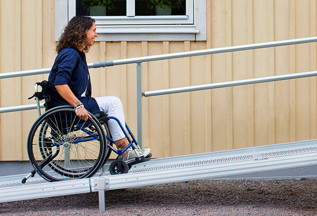 Kuvassa nainen liikkuu pyörätuolilla ramppia ylös.