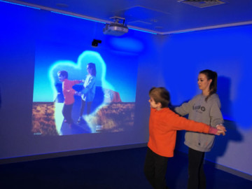 Kuvassa omireflex mobile interaktiivinen seinä käytössä nainen ja poika etualalla